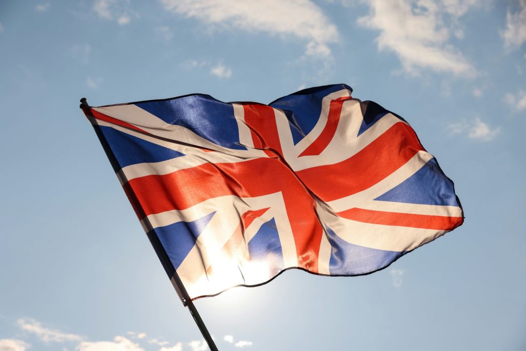 UK Great Britain flag waving in cloudy blue sky